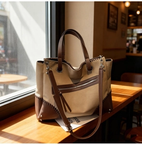 Detailed shot of retro khaki canvas tote bag with brown leather base and side stitching