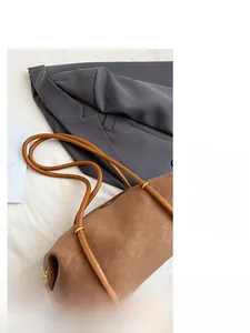 Vue détaillée d'un sac hobo en cuir marron avec bandoulières et fermeture éclair dorée