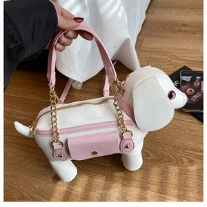 Macro detail of cute puppy shaped handbag with pink accents and golden chain strap