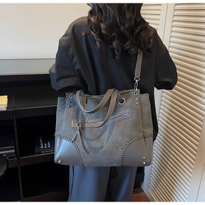 Detail of grey tote bag showing contrast stitching, matte texture, and detachable strap
