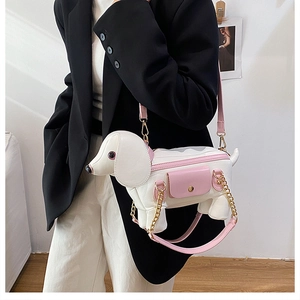 Detail of dachshund-shaped crossbody bag featuring pink leather accents and gold chain