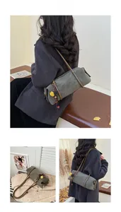 Vue détaillée du sac cylindre en daim gris avec pompon coloré et breloque en perles