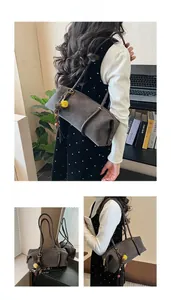 Vue détaillée du sac cylindre en daim taupe avec breloque florale et pompons