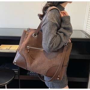 Brown suede tote bag with leather corner patches and zipper pocket shown on model