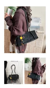 Détail du sac sous l'aisselle en daim noir avec pompon décoratif et fine bandoulière