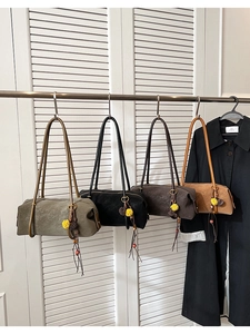 Détail de sacs polochons en suède en quatre couleurs avec breloques à pompons fleuris