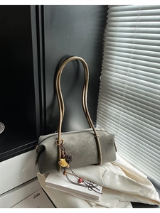 Détail du sac baguette vintage gris-vert avec bretelles en bronze et breloque à pompon ethnique