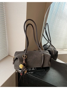 Détail du sac baguette café foncé avec texture en daim et pendentif floral délicat