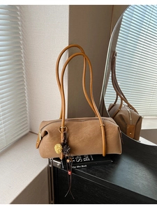 Gros plan du sac tonneau rétro marron avec texture daim et pendentif fleur sur bois