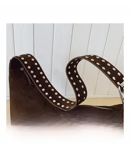 Detail of dark brown suede shoulder bag featuring silver studded strap and metal zipper