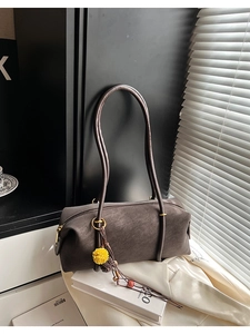 Détail du sac baguette gris anthracite avec fines lanières et pompon jaune vif