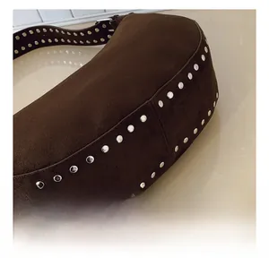 Detail shot of silver rivets on dark brown suede shoulder bag with retro biker style finish