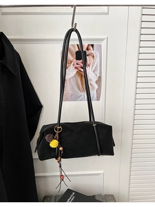 Détail d'un sac baguette noir avec garnitures dorées et pendentif floral à perles