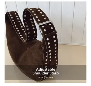 Close-up of brown suede hobo bag with adjustable wide strap and silver metal rivets