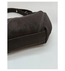 Detail of dark brown leather bag showing reinforced bottom and white contrast stitching