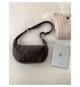 Detail of dark brown suede crescent bag with white contrast stitching and leather strap