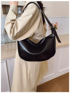 Detail of black crescent hobo bag featuring silver rivets on the shoulder strap