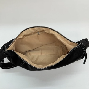 Black half-moon shoulder bag with white contrast stitching and spacious interior
