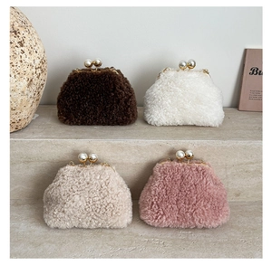 Multiple colors of plush handbags with pearl clasps displayed on stone steps