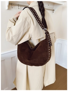 Detailed side view of deep brown suede hobo bag with silver rivets on model in coat