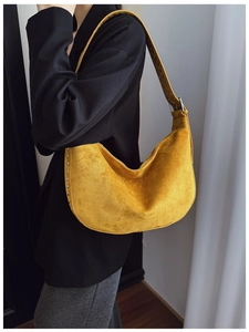 Detail of yellow suede underarm bag featuring silver studs and adjustable shoulder strap
