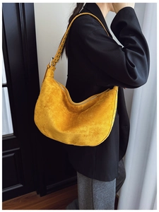 Detail of yellow suede shoulder bag with silver rivet studs worn with a black blazer