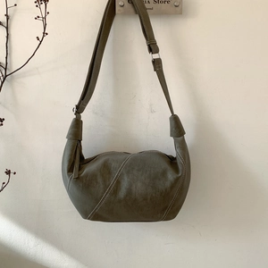 Detail of olive green crescent crossbody bag with white stitching and leather texture