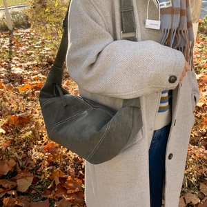 Detail view of dark grey crescent bag with bold contrast stitching and matte leather texture