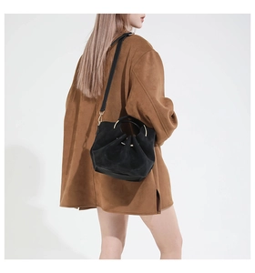 Detail der schwarzen Wildledertasche mit Falten, Goldgriff und schmalem Schultergurt