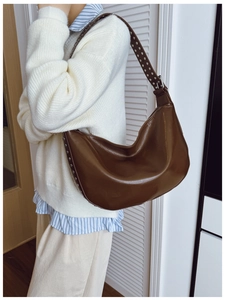 Detail of silver rivets on dark brown crescent hobo bag with glossy leather texture