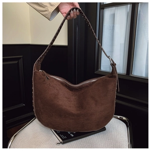 Detail of the high-quality dark brown suede texture and rivet strap of the hobo bag