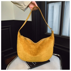 Detail view of ginger suede hobo bag featuring wide strap with metallic eyelets