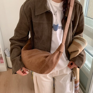 Detail of brown suede crescent bag with white contrast stitching and wide shoulder strap