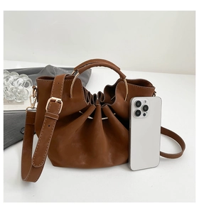 Detailansicht der dunkelbraunen Falten-Handtasche mit goldenem Ringgriff und Gurt