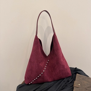 Retro burgundy suede hobo bag with silver studs on elegant black silk background