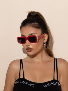 Gros plan sur des lunettes de soleil rouges rectangulaires avec détails en métal doré