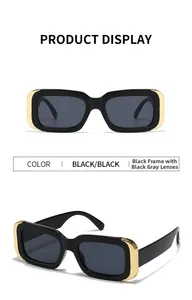 Détail de lunettes de soleil rectangulaires noires avec coins dorés et verres gris foncé