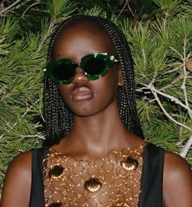 Detail of green leaf-shaped sunglasses with gold scallop metal chain body jewelry