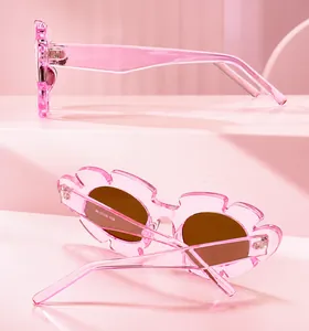 Detail view of pink flower-shaped children's sunglasses with dark brown lenses from multiple angles
