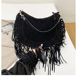 Detail of black suede crescent bag featuring long fringe tassels and gold metal hooks