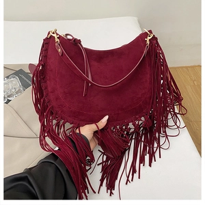 Close-up of bohemian burgundy suede half-moon bag featuring dense fringe tassels