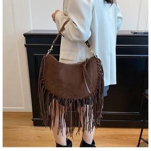 Close-up of brown suede saddle bag featuring long fringe and gold hardware details