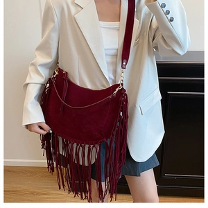 Close-up of burgundy suede tassel bag shoulder strap and fringe details on model