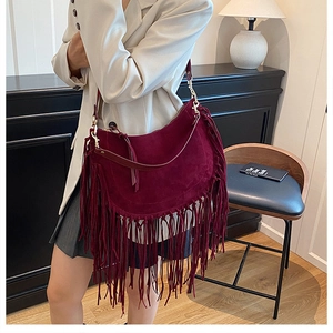 Close-up of wine red suede hobo bag featuring long bohemian tassels and gold hardware