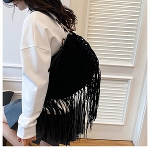 Detail of bohemian black fringe shoulder bag showing suede texture and long tassels