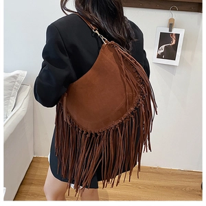 Detail of bohemian brown suede crescent bag with long fringes and gold metal hardware