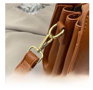 Detail of high-quality golden metal hook and strap stitching on brown leather handbag