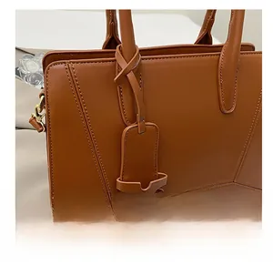 Detail of caramel brown leather handbag featuring unique tied charm and gold hardware