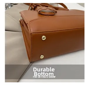 Detail of caramel leather handbag bottom featuring protective gold metal feet and stitching