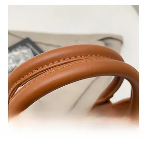 Macro shot of comfortable thickened cylindrical handle with fine stitching on brown handbag